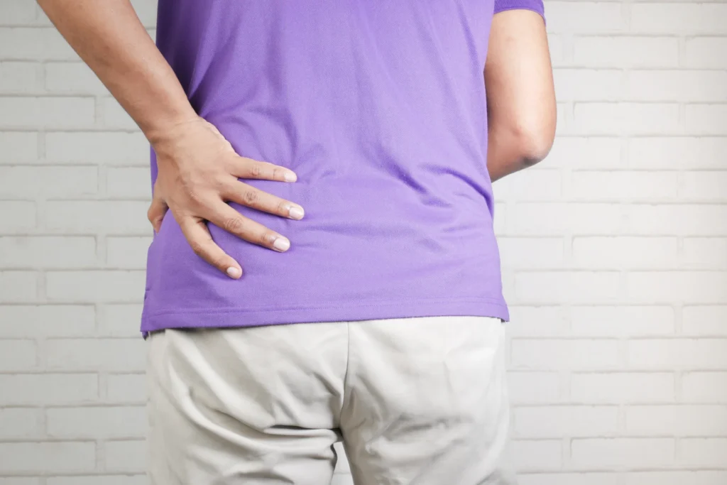 adult hands holds lower back in purple shirt 2026 03 17 20 19 24 utc