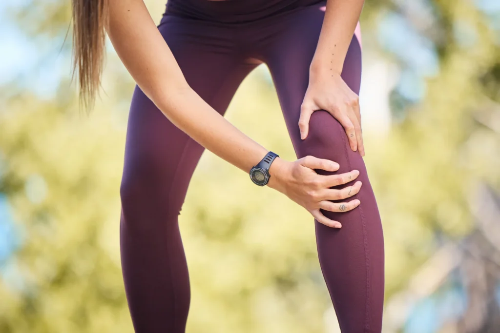 woman massaging knee outside in natural light 2026 01 09 10 54 24 utc