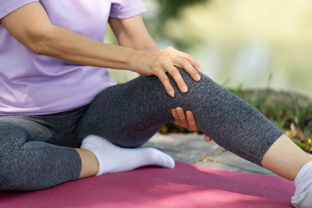 woman massaging knee sitting outside in gray leggi 2026 03 25 08 37 26 utc