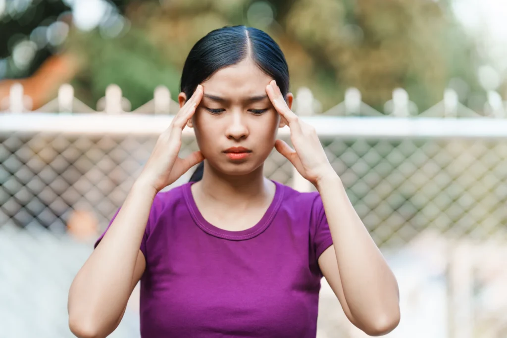 woman with headache rubbing temples outdoors 2026 03 20 03 06 05 utc