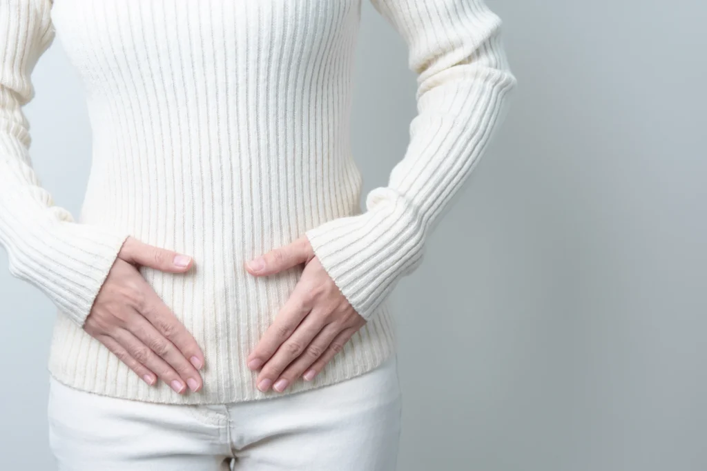 adult woman hands on stomach in white top 2026 03 25 00 45 06 utc