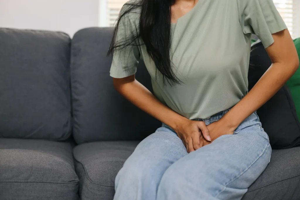woman sitting on couch holding lower abdomen 2026 03 24 12 41 40 utc 1